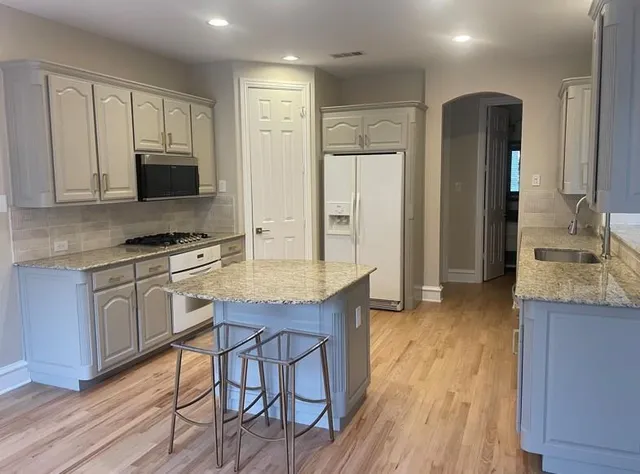 a kitchen with granite countertop a stove refrigerator and microwave