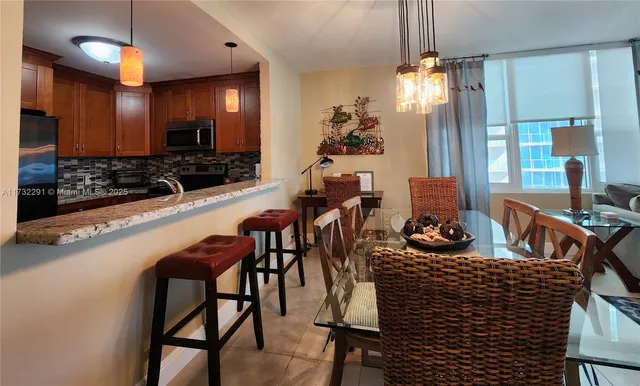 a kitchen with stainless steel appliances kitchen island granite countertop a refrigerator a stove and a sink with wooden cabinets