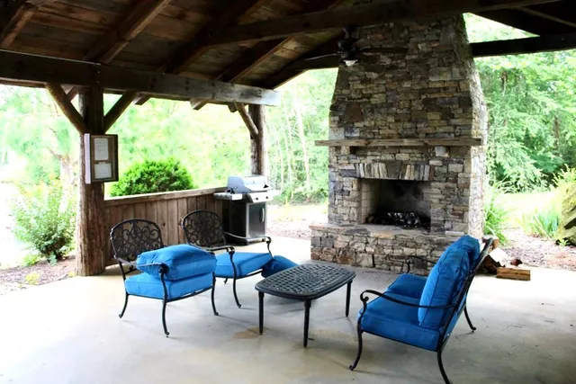 a outdoor living space with furniture a fireplace and a floor to ceiling window