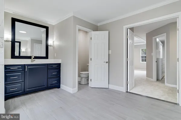 a view of an empty room with wooden floor and a ceiling fan