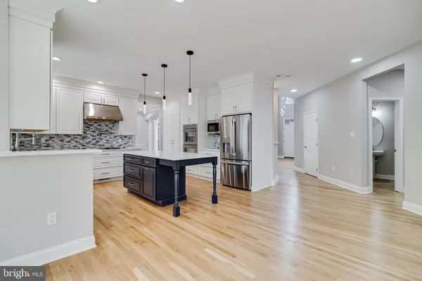 a large kitchen with stainless steel appliances kitchen island granite countertop a large counter top and wooden floors