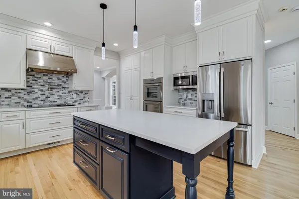 a kitchen with kitchen island a sink stove and white cabinets with wooden floor