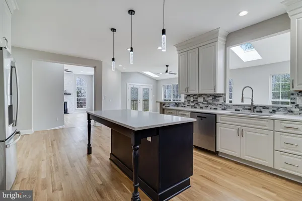 a kitchen with kitchen island granite countertop a sink a counter top space stainless steel appliances and cabinets