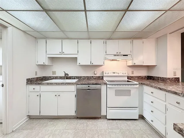 a kitchen with granite countertop white cabinets and white appliances
