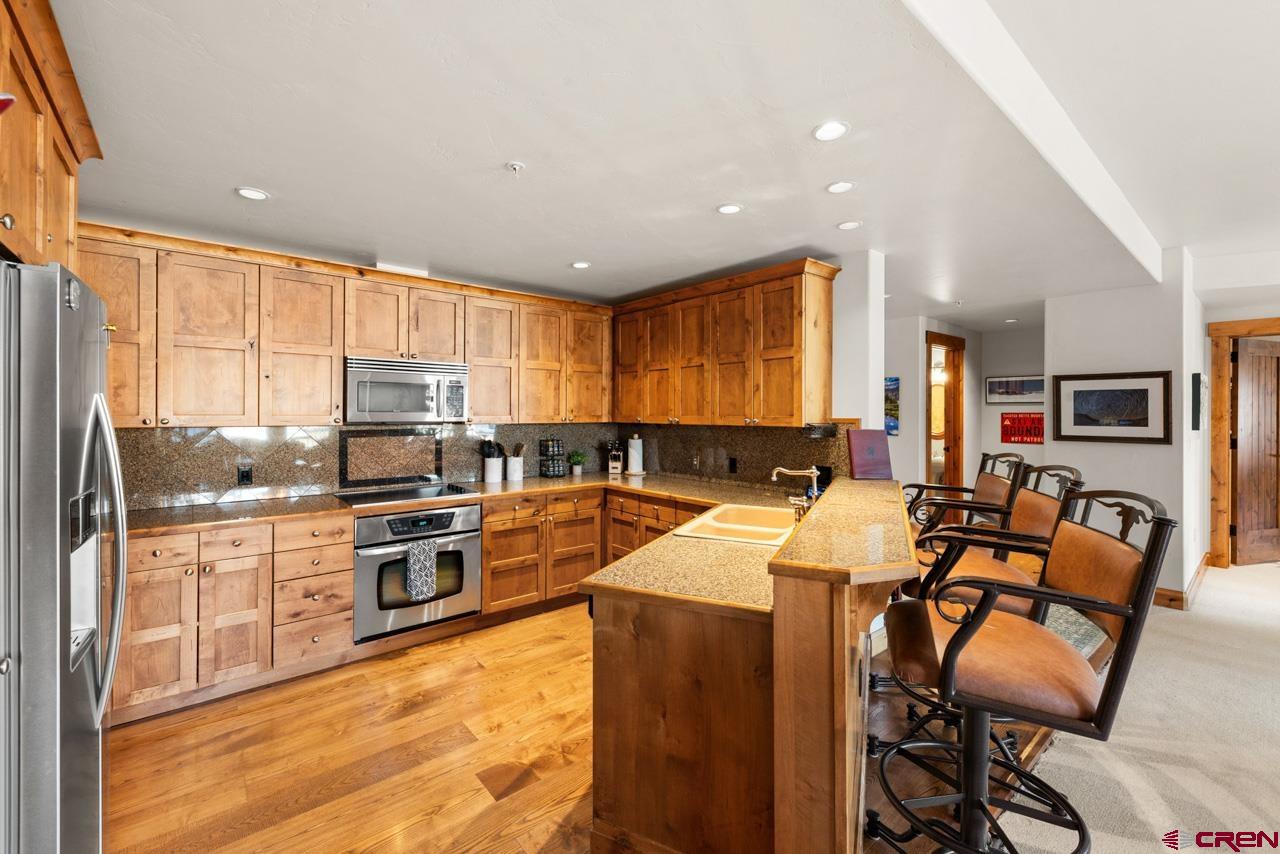 14 Hunter Hill Road, Unit A208 Crested Butte, CO 81225 - Photo 26 of 43 a large kitchen with stainless steel appliances kitchen island granite countertop a stove top oven a sink a dining table and chairs with wooden floor