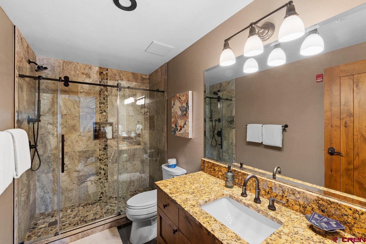 14 Hunter Hill Road, Unit A208 Crested Butte, CO 81225 - Photo 32 of 43 a bathroom with a granite countertop sink toilet a shower and a mirror