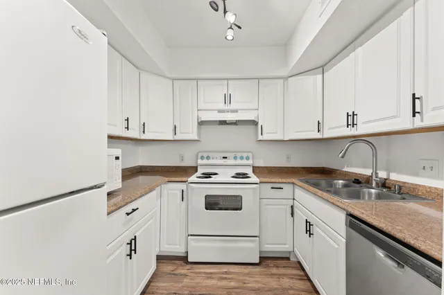 a kitchen with granite countertop white cabinets and white appliances
