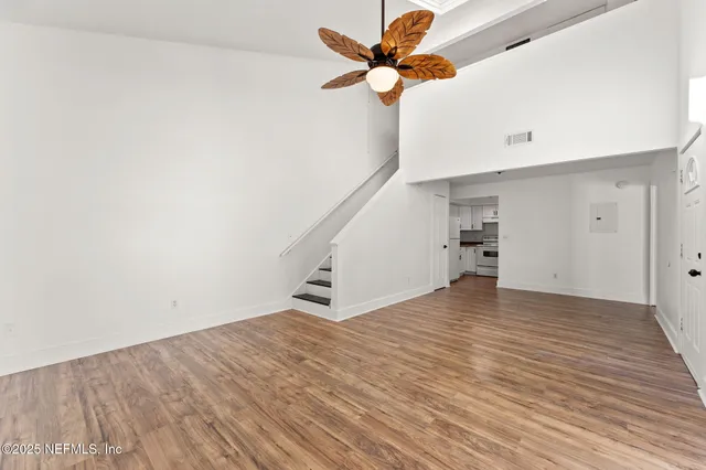 a view of empty room with wooden floor and fan
