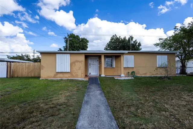 a view of a backyard with plants and large tree