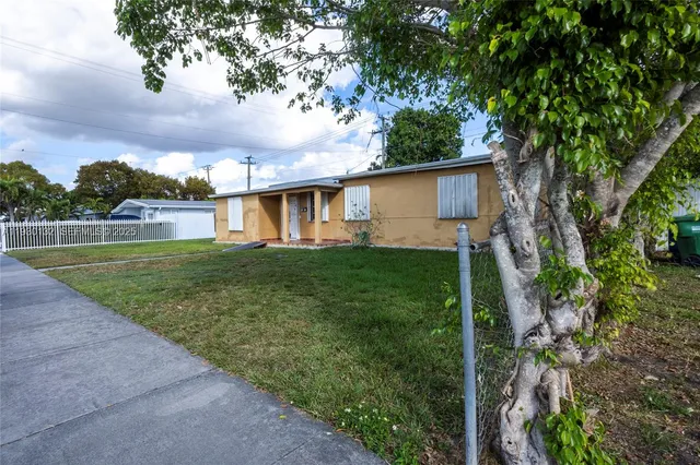 a view of a house with a big yard plants and large trees