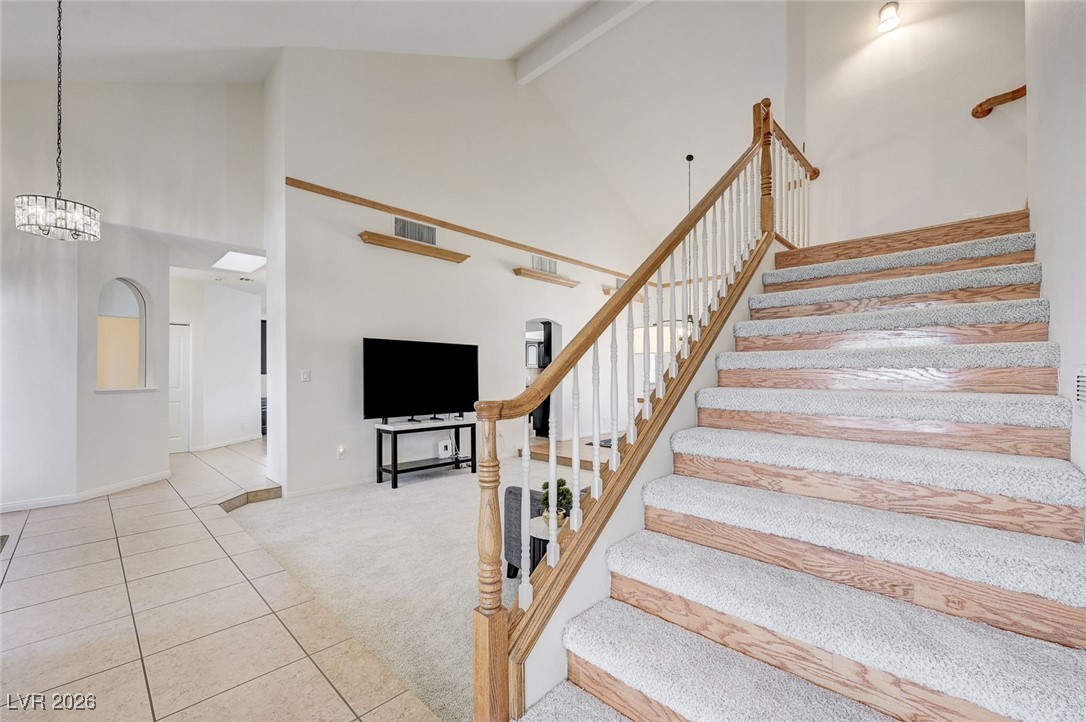 2955 El Camino Road Las Vegas, NV 89146 - Photo 37 of 99 Stairs featuring a high ceiling, carpet floors, tile patterned flooring, and beamed ceiling