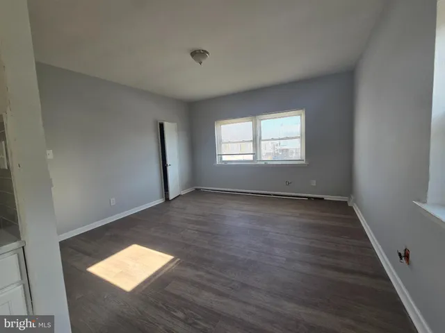 a view of empty room with wooden floor and window