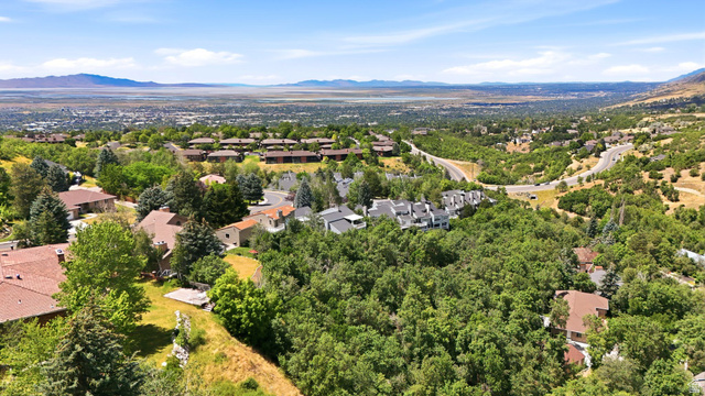 1979 Cave Hollow Way Bountiful, UT 84010 - Photo 49 of 59 Expansive aerial perspective showcasing a residential area with varied housing styles, surrounded by abundant mature trees and natural landscaping