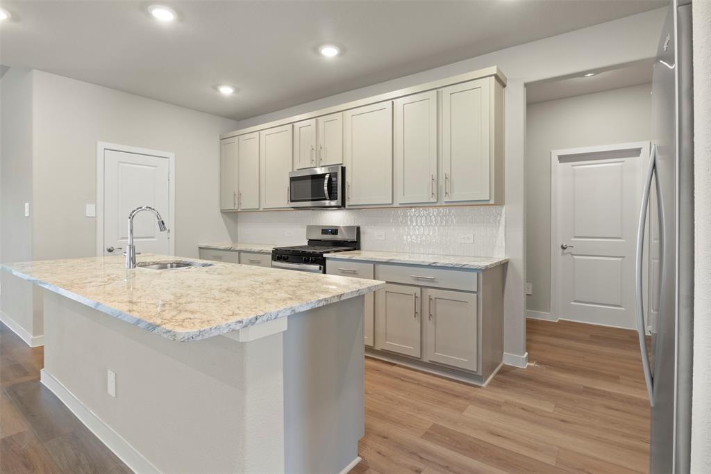 2220 Currents Road Princeton, TX 75407 - Photo 11 of 31 Expansive kitchen island with a stone countertop, stainless steel sink, and a gooseneck faucet