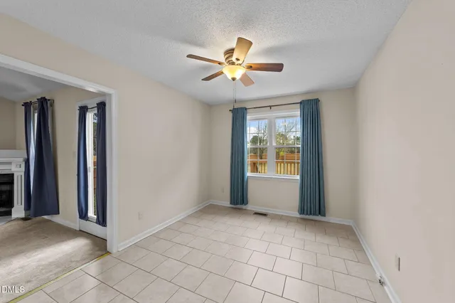 a view of an empty room with window and chandelier fan