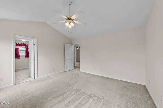 a view of an empty room with chandelier fan