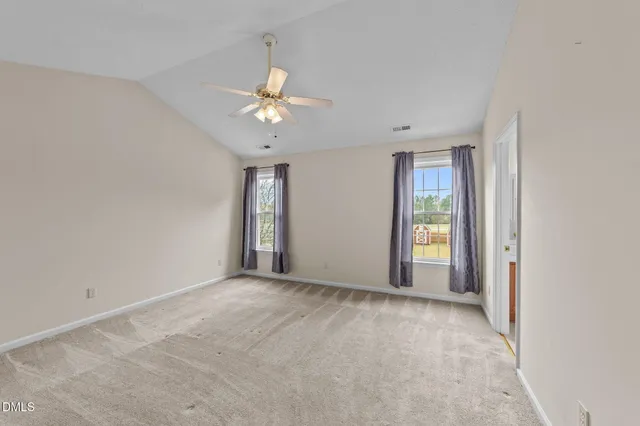 an empty room with chandelier fan and windows