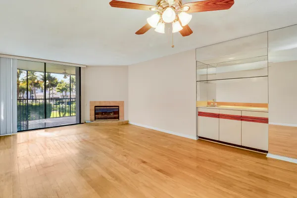 a view of a big room with wooden floor a ceiling fan and window