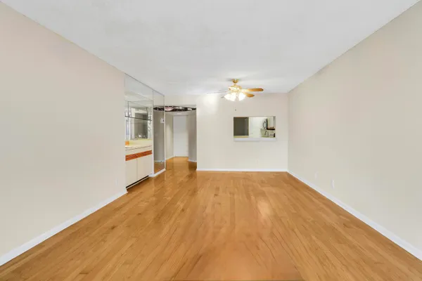 an empty room with a chandelier fan and a wooden floor