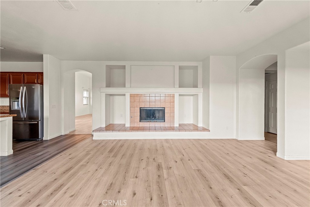 4660 Spice Street Lancaster, CA 93536 - Photo 16 of 42 an empty room with wooden floor a fireplace and windows