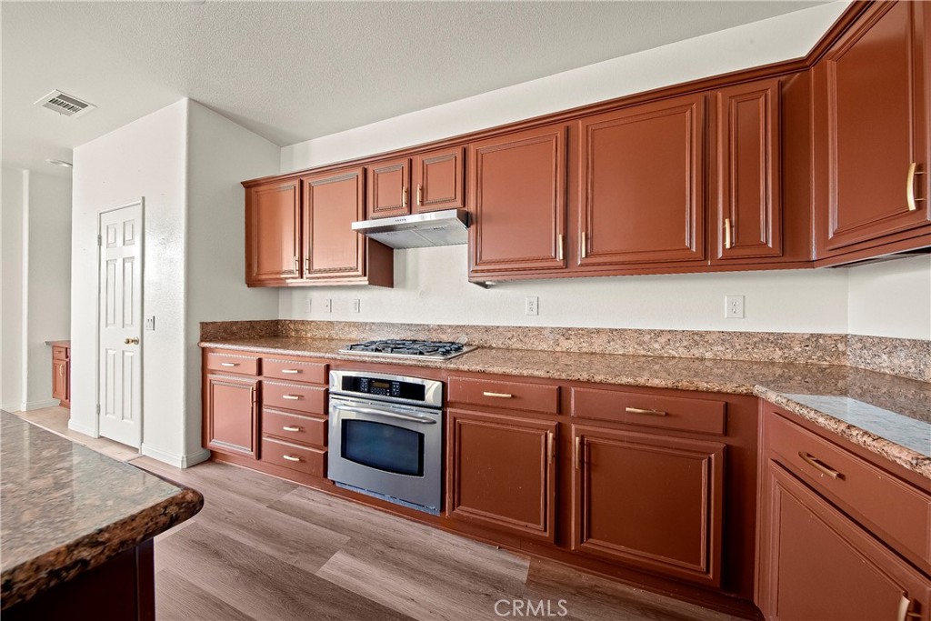 4660 Spice Street Lancaster, CA 93536 - Photo 20 of 42 a kitchen with granite countertop wooden cabinets a sink and dishwasher