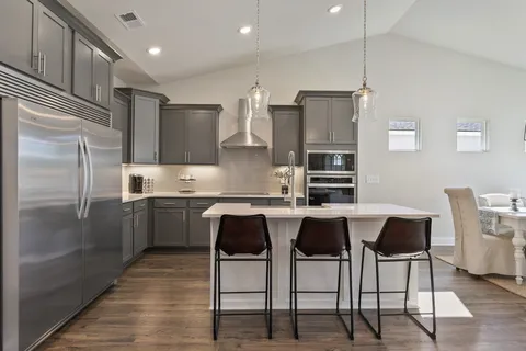a kitchen with stainless steel appliances granite countertop a sink a stove a refrigerator and island