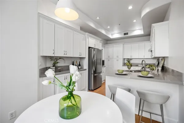 a kitchen with stainless steel appliances granite countertop a white refrigerator a sink a stove a dining table and chairs