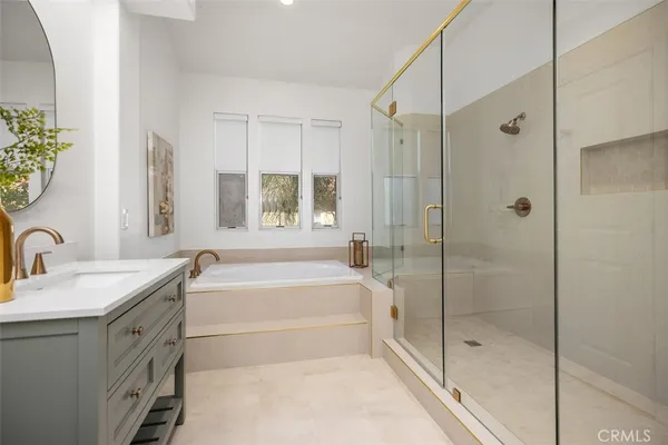 a spacious bathroom with a granite countertop sink a mirror a bathtub and shower