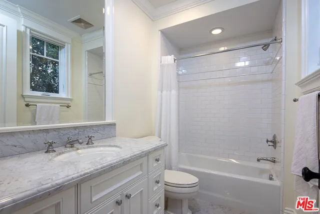 a bathroom with a granite countertop sink toilet and mirror