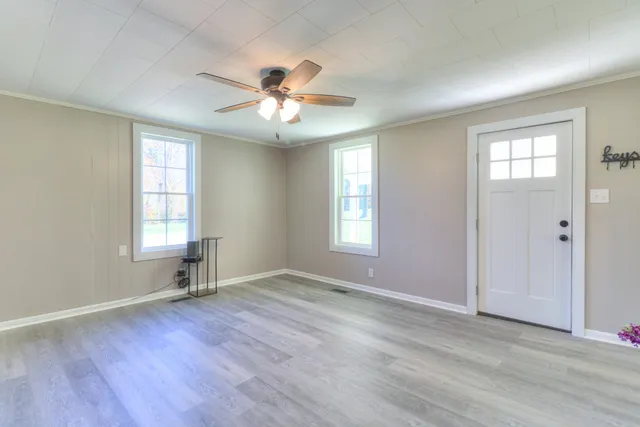 a view of an empty room with a window and wooden floor