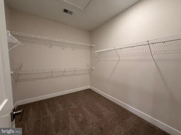 an empty room with windows and view of kitchen