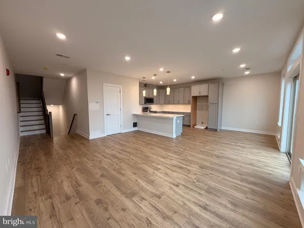 a large white kitchen with kitchen island a sink wooden floor and stainless steel appliances