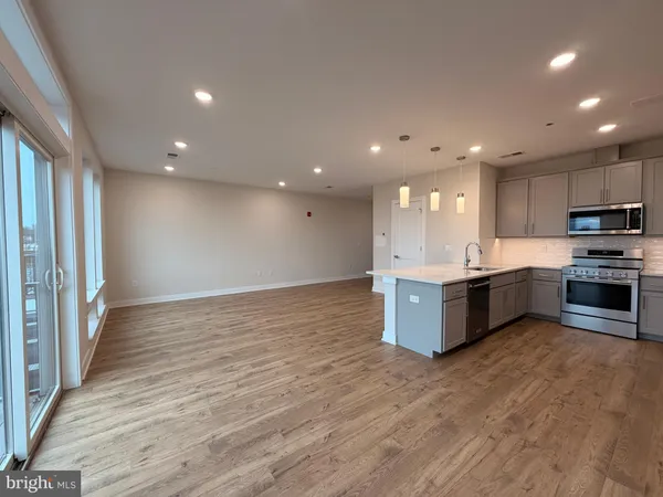 a large kitchen with stainless steel appliances granite countertop a large counter top a sink and a refrigerator