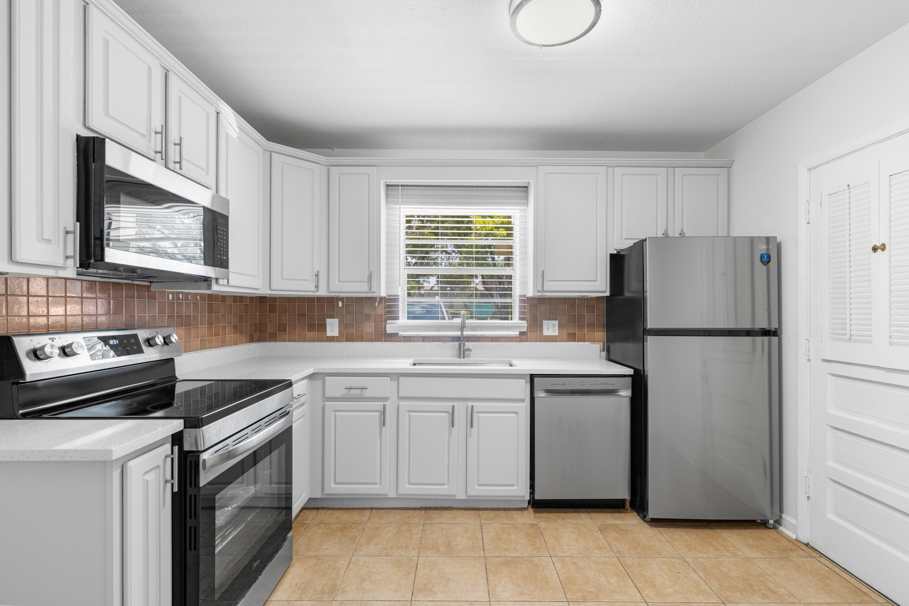 10693 North Military Trail, Unit 7 Palm Beach Gardens, FL 33410 - Photo 9 of 28 a kitchen with a stove a sink and a refrigerator