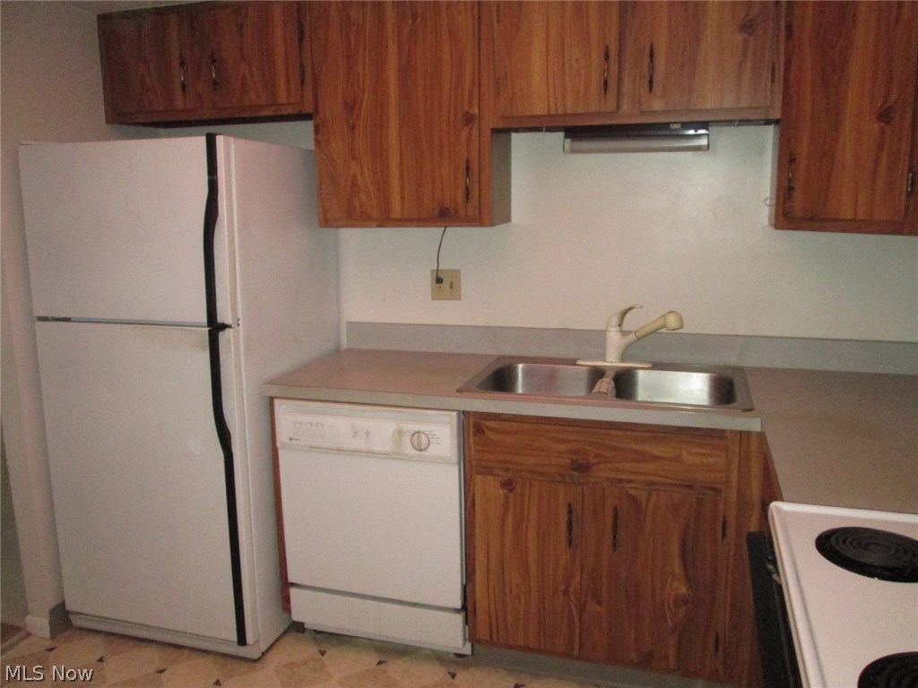 Kitchen with all kitchen appliances that stay with the condo, including the refrigerator, built-in dishwasher and electric stove.