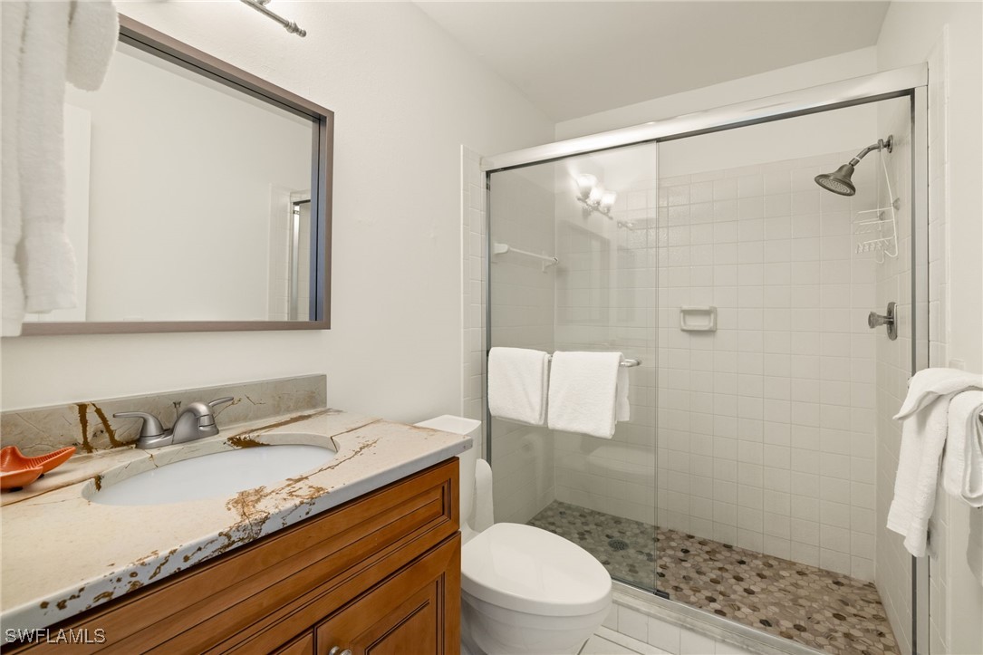 5117 Sea Bell Road, Unit C207 Sanibel, FL 33957 - Photo 23 of 43 a bathroom with a granite countertop sink a mirror a toilet and shower