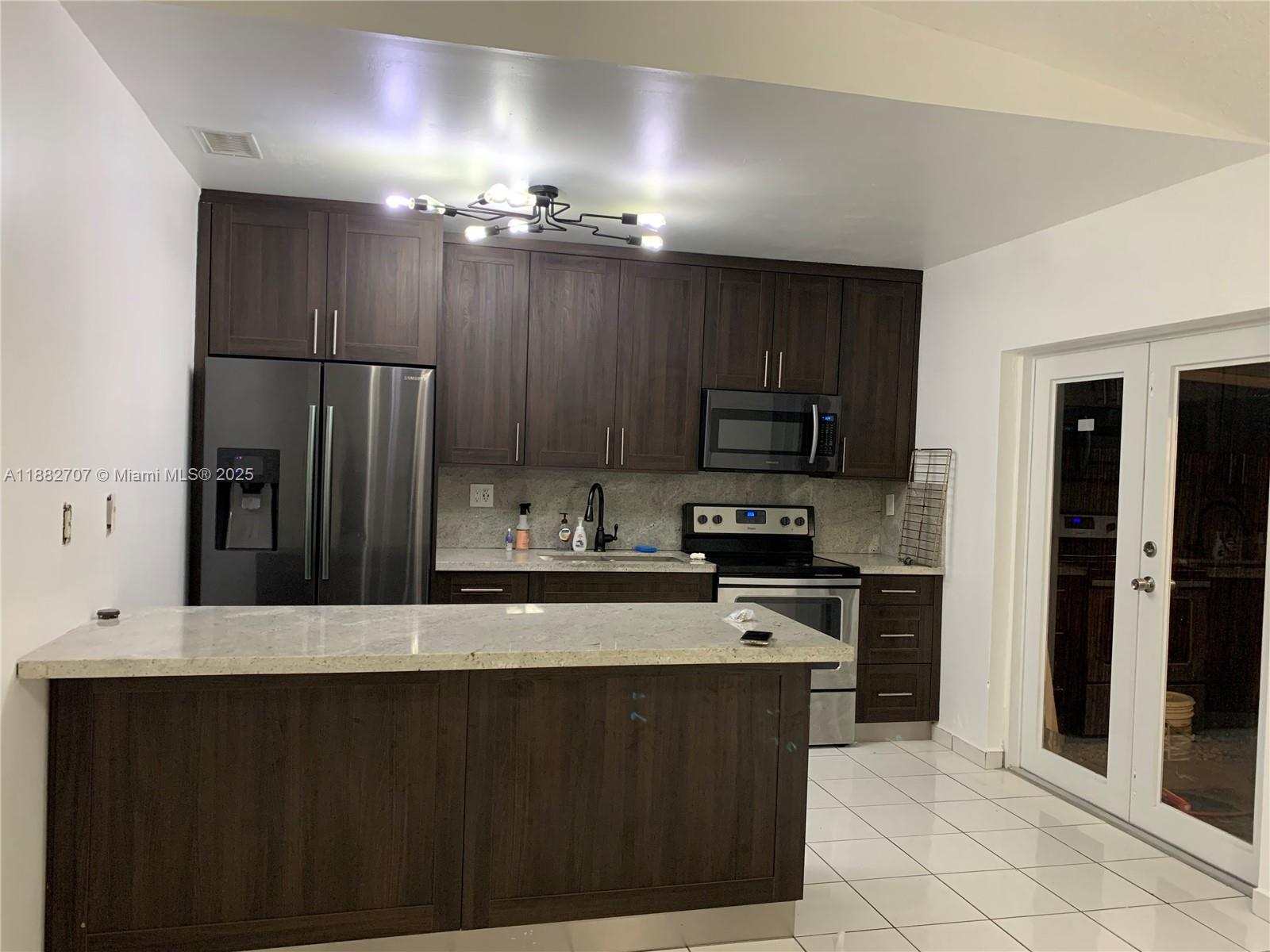 a kitchen with a sink a microwave a refrigerator and cabinets