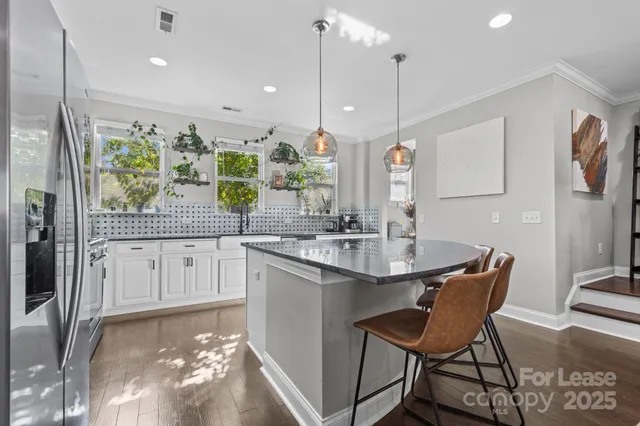 a kitchen with kitchen island granite countertop a sink and white cabinets