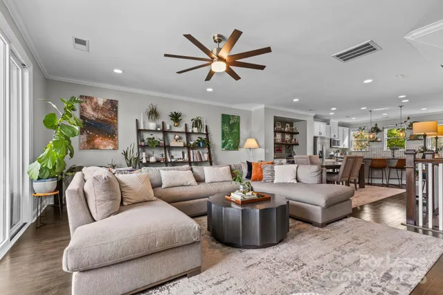 a living room with furniture kitchen view and a chandelier