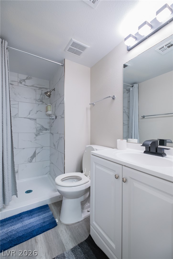 6356 West Viking Road Las Vegas, NV 89103 - Photo 9 of 51 A modern bathroom features a tiled shower surround alongside a white vanity with updated fixtures.