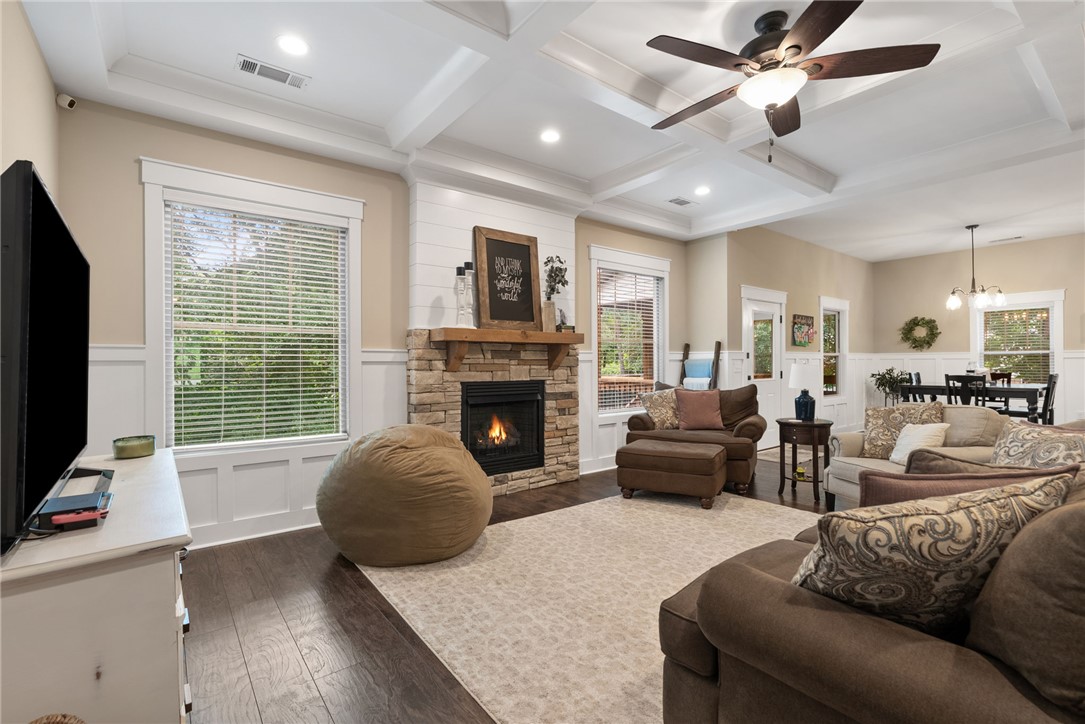 201 Hearthstone Drive Anderson, SC 29621 - Photo 10 of 49 A comforting living space features a stone fireplace, dark wood floors, and a bright tray ceiling.