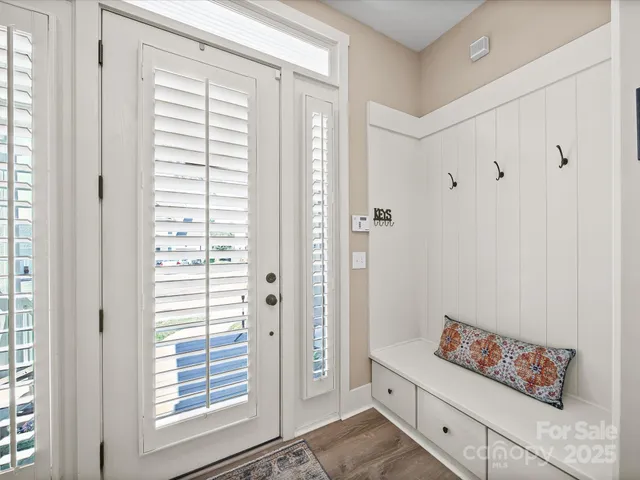 a view of a hallway to a livingroom with wooden floor and stairs