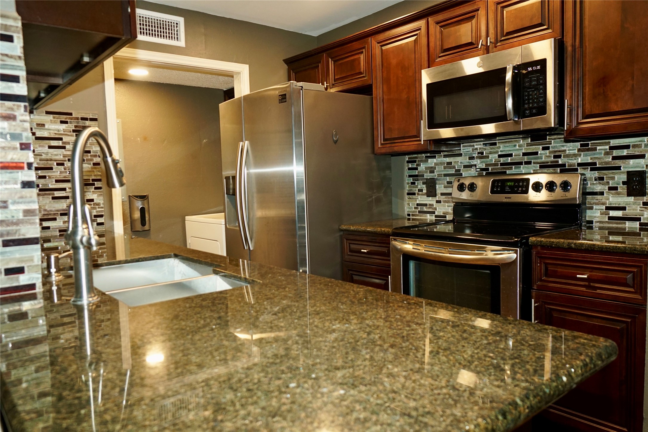 a kitchen with stainless steel appliances granite countertop a stove a sink and a microwave