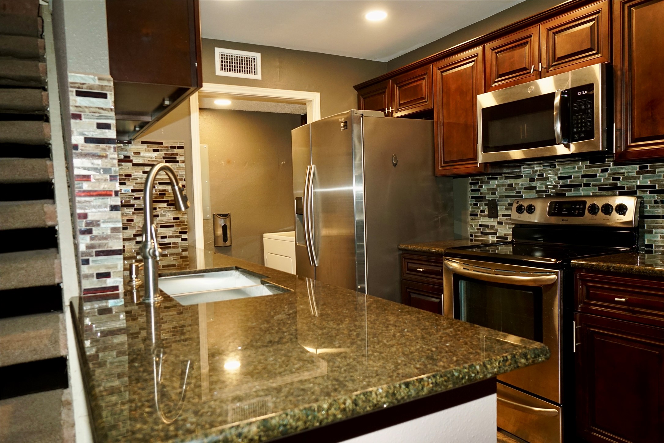 8275 Sands Point Drive, Unit 176 Houston, TX 77036 - Photo 5 of 31 a kitchen with stainless steel appliances granite countertop a refrigerator a stove and a sink with wooden floor