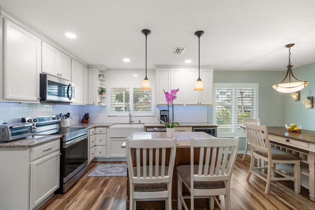 7133 Augusta Boulevard Seminole, FL 33777 - Photo 12 of 54 a kitchen with kitchen island granite countertop a sink a stove a oven a dining table and chairs