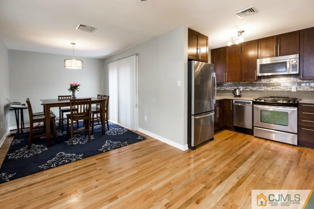 106 Normandy Road Colonia, NJ 07067 - Photo 13 of 25 a kitchen with stainless steel appliances granite countertop a stove refrigerator and a dining table
