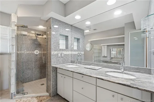a bathroom with a granite countertop sink mirror and shower
