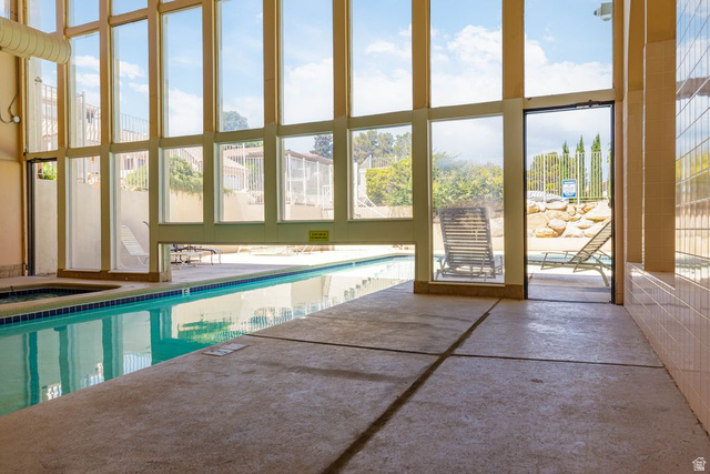 2158 Balboa Way St. George, UT 84770 - Photo 30 of 40 Indoor swimming pool area with expansive windows, an integrated spa, and direct access to an outdoor patio
