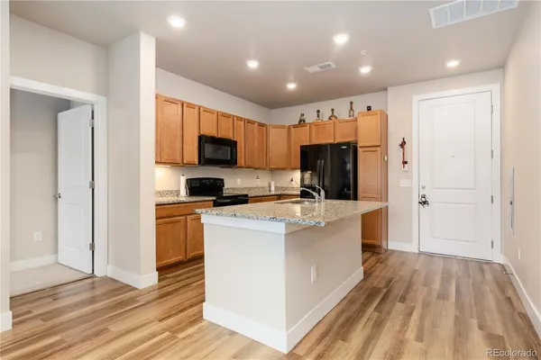 a kitchen with stainless steel appliances granite countertop a refrigerator oven a sink dishwasher and white cabinets with wooden floor