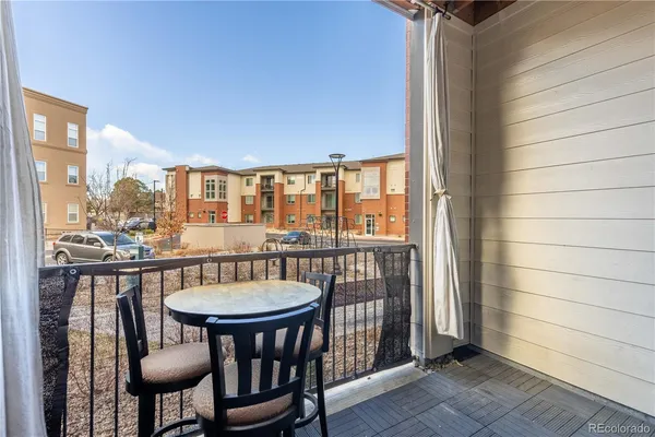 a balcony with table and chairs and potted plants